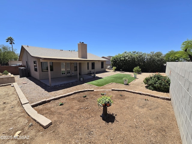 rear view of property featuring a shingled roof, a fenced backyard, a patio, and a chimney