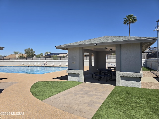 community pool with a fenced backyard and a patio area