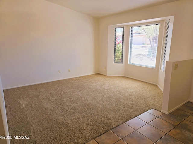 carpeted empty room with tile patterned flooring and baseboards