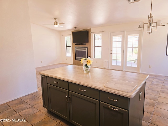 kitchen featuring tile patterned flooring, visible vents, a ceiling fan, a kitchen island, and open floor plan