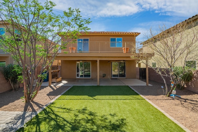 rear view of property with a fenced backyard, a patio area, a balcony, a yard, and stucco siding