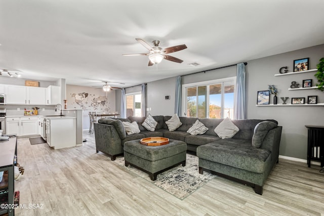 living room with light wood finished floors, baseboards, a ceiling fan, and visible vents