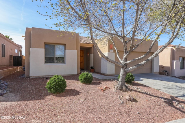 southwest-style home featuring concrete driveway, a tiled roof, a garage, and stucco siding