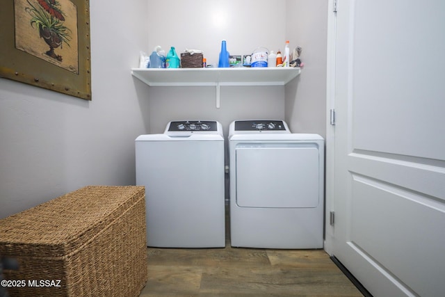 clothes washing area featuring laundry area, washer and clothes dryer, and wood finished floors