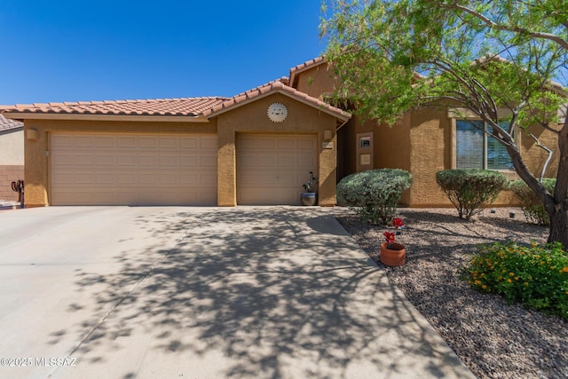 mediterranean / spanish house featuring stucco siding, a tiled roof, driveway, and an attached garage