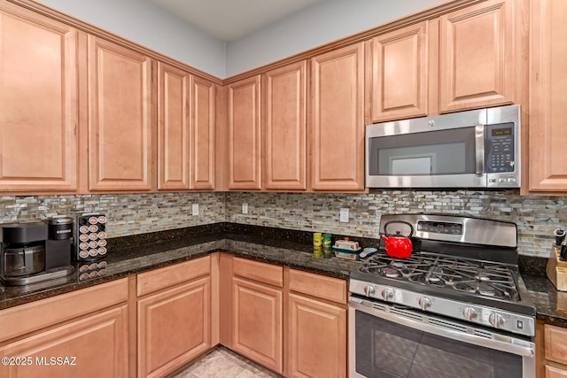 kitchen with dark stone counters, appliances with stainless steel finishes, and tasteful backsplash