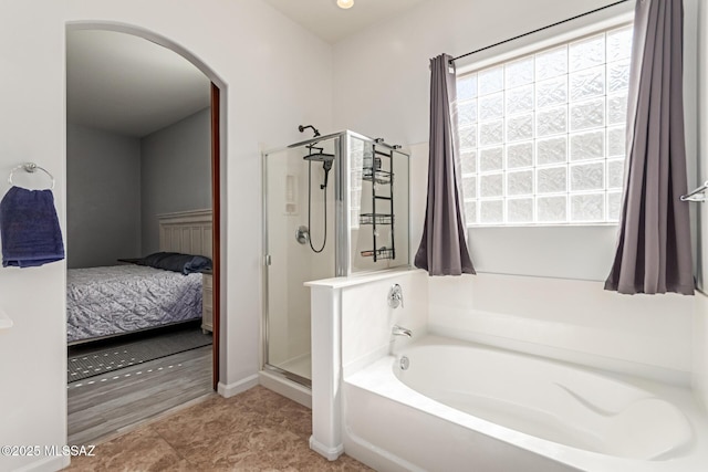 ensuite bathroom featuring a bath, a shower stall, and connected bathroom