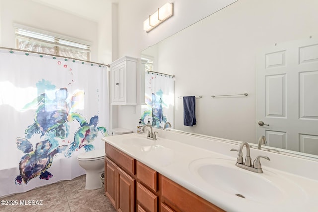 bathroom featuring double vanity, toilet, tile patterned floors, and a sink