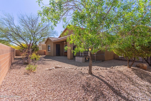 back of house with a fenced backyard, stucco siding, a tile roof, a patio area, and a ceiling fan