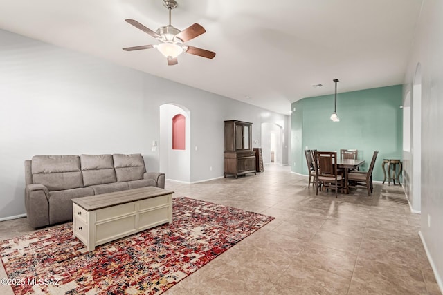 living area with arched walkways, ceiling fan, and baseboards
