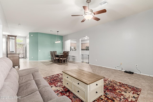 living room featuring baseboards, visible vents, arched walkways, and a ceiling fan