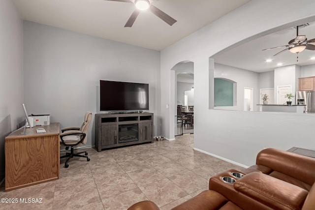 living room featuring recessed lighting, ceiling fan, a glass covered fireplace, baseboards, and arched walkways