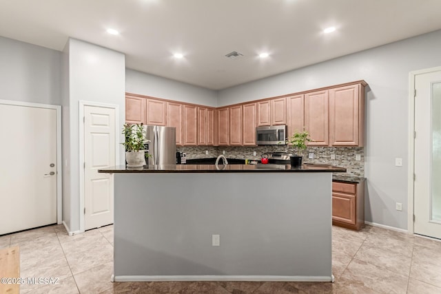 kitchen with decorative backsplash, stainless steel appliances, a kitchen island, dark countertops, and visible vents