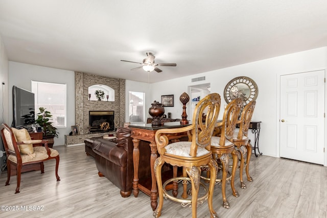 3825 W Perseus St, Tucson, AZ 85742 - living area featuring a large fireplace, a ceiling fan, visible vents, and light wood finished floors