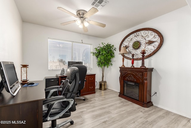 3825 W Perseus St, Tucson, AZ 85742 - office space with visible vents, a ceiling fan, light wood-type flooring, baseboards, and a glass covered fireplace