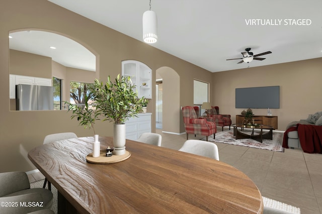 38876 S Serenity Ln, Tucson, AZ 85739 - dining space featuring ceiling fan, arched walkways, baseboards, and light tile patterned floors