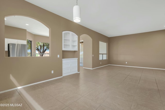 38876 S Serenity Ln, Tucson, AZ 85739 - spare room with light tile patterned floors, arched walkways, a healthy amount of sunlight, and baseboards