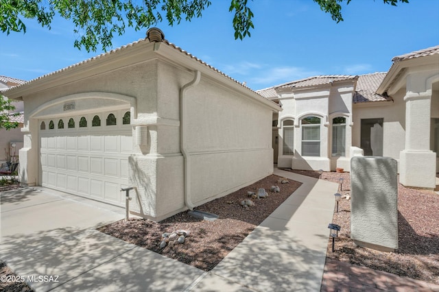 38876 S Serenity Ln, Tucson, AZ 85739 - view of property exterior featuring an attached garage, a tiled roof, driveway, and stucco siding