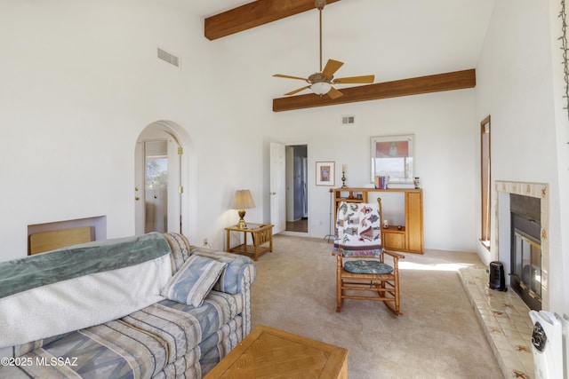 280 W Oak Hills Dr, Oracle, AZ 85623 - living room featuring arched walkways, ceiling fan, a glass covered fireplace, beamed ceiling, and light carpet