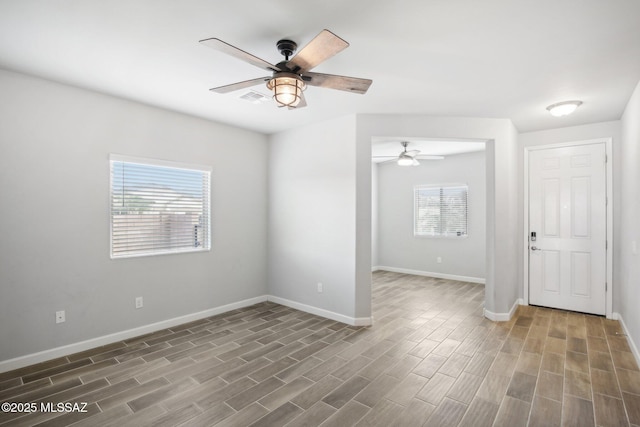 spare room featuring wood finished floors, a ceiling fan, and baseboards
