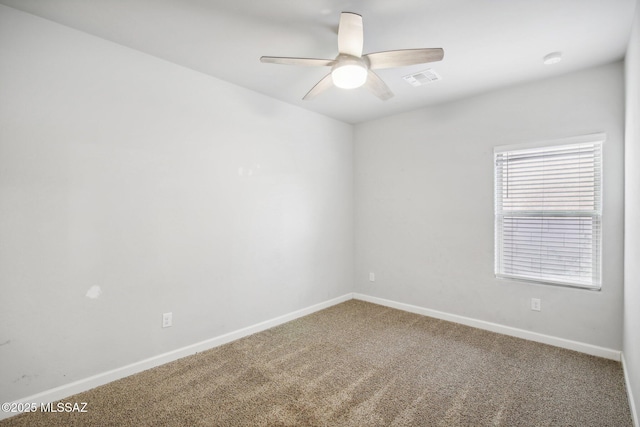 carpeted empty room with baseboards, a ceiling fan, and visible vents