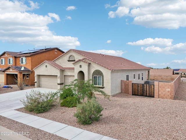 mediterranean / spanish home featuring driveway, a tiled roof, fence, a garage, and stucco siding