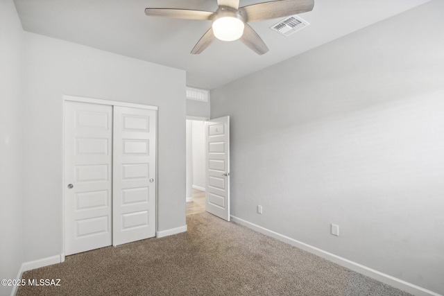 unfurnished bedroom with carpet, visible vents, a closet, baseboards, and ceiling fan