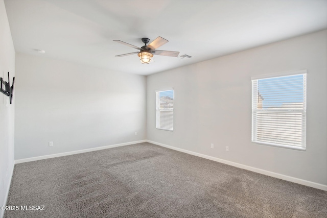 unfurnished room with carpet flooring, baseboards, visible vents, and ceiling fan