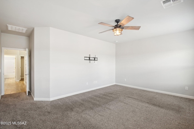 carpeted spare room featuring baseboards, visible vents, and ceiling fan