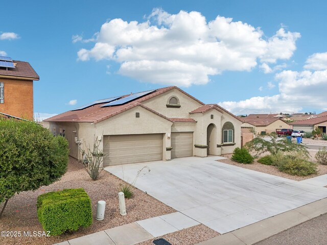mediterranean / spanish home with stucco siding, concrete driveway, solar panels, and a garage