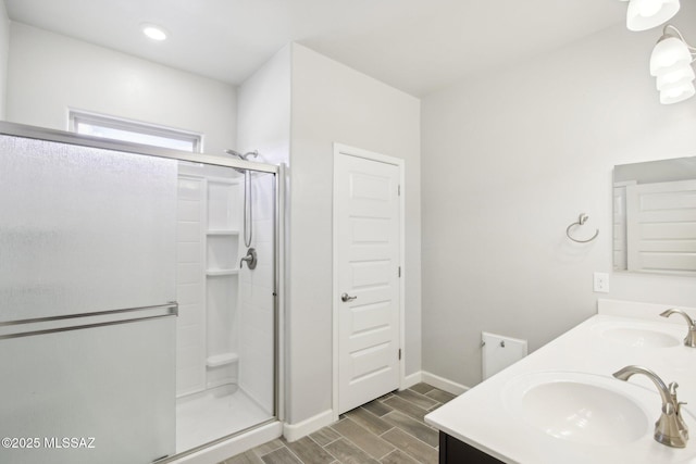 full bath featuring double vanity, wood finish floors, a stall shower, and a sink