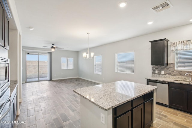 kitchen with visible vents, decorative backsplash, wood finish floors, appliances with stainless steel finishes, and ceiling fan with notable chandelier