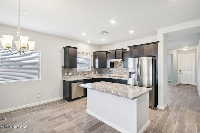 kitchen with stainless steel appliances, a sink, visible vents, dark brown cabinetry, and decorative backsplash