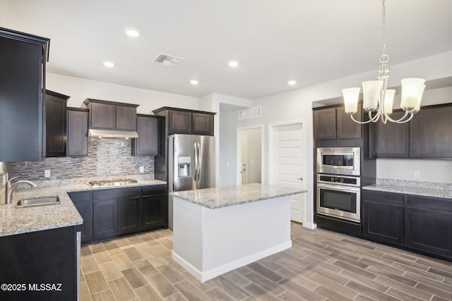 kitchen with light wood-style flooring, a sink, tasteful backsplash, visible vents, and appliances with stainless steel finishes