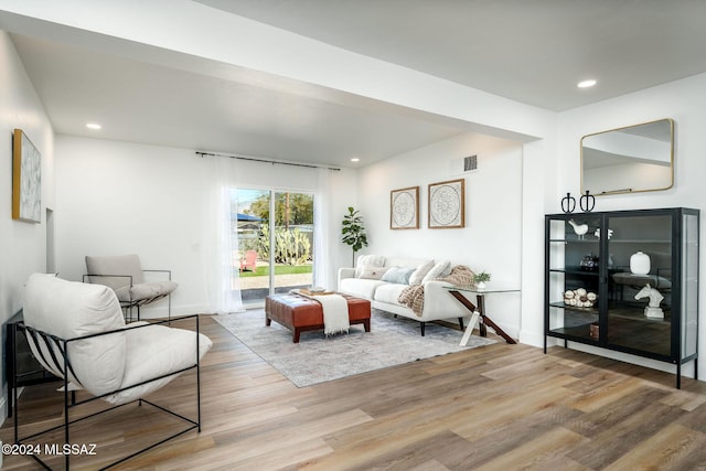 living room featuring recessed lighting, wood finished floors, visible vents, and baseboards