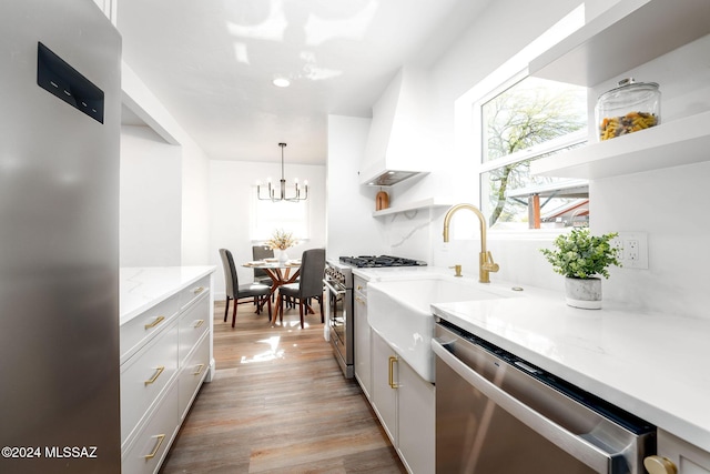 kitchen featuring open shelves, light wood-style floors, stainless steel appliances, a notable chandelier, and light stone countertops