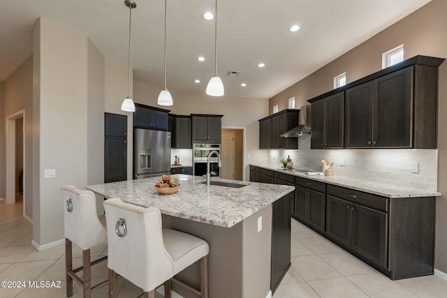 5152 W Heritage Gateway Pl, Marana, AZ 85658 - kitchen with stainless steel appliances, a sink, light tile patterned flooring, decorative backsplash, and wall chimney range hood