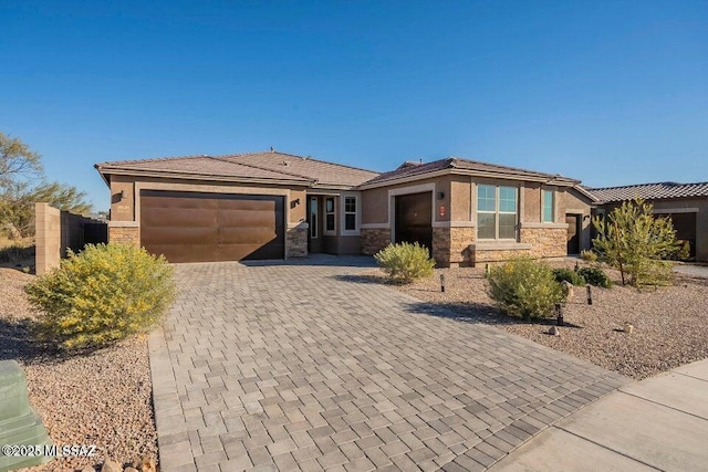 10965 N Cormac Ave, Tucson, AZ 85742 - view of front facade featuring an attached garage, stone siding, stucco siding, and decorative driveway