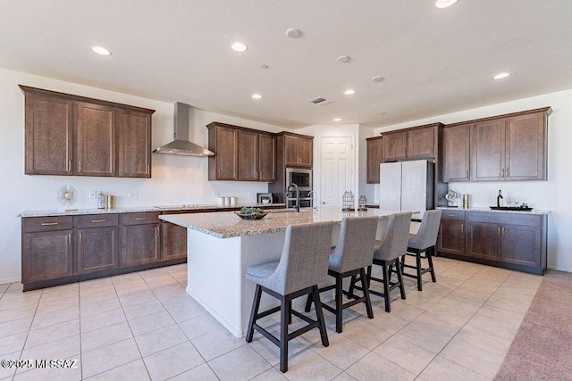 10965 N Cormac Ave, Tucson, AZ 85742 - kitchen with wall chimney range hood, stainless steel microwave, recessed lighting, light tile patterned floors, and a breakfast bar area