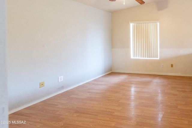 empty room with ceiling fan, vaulted ceiling, baseboards, and light wood-type flooring