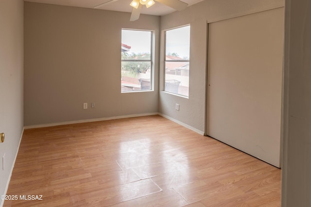 unfurnished bedroom with a closet, light wood finished floors, baseboards, and a ceiling fan