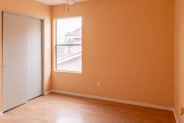 unfurnished bedroom with a closet, light wood finished floors, and baseboards