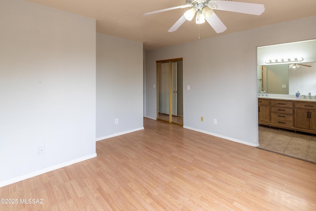 unfurnished bedroom with light wood-style floors, baseboards, ensuite bathroom, and a sink