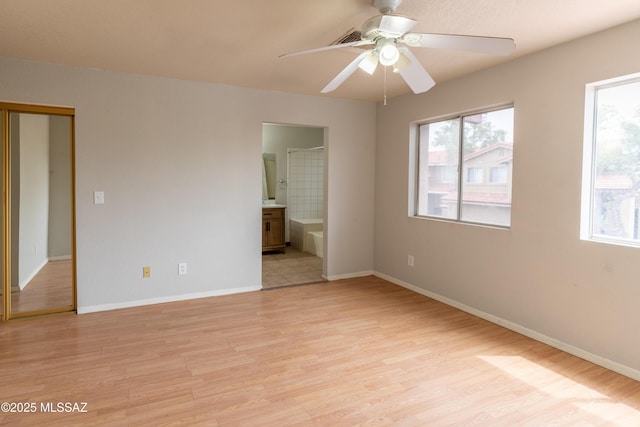 unfurnished bedroom featuring light wood-style flooring, baseboards, and multiple windows