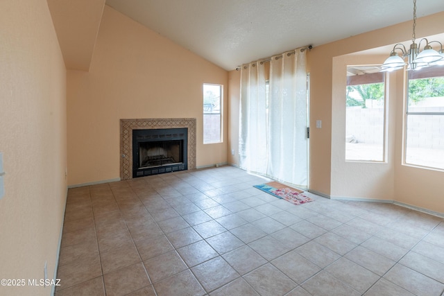 unfurnished living room with lofted ceiling, a notable chandelier, tile patterned floors, and a tiled fireplace