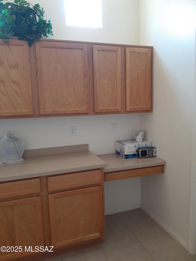 kitchen featuring light countertops, built in study area, and light tile patterned flooring