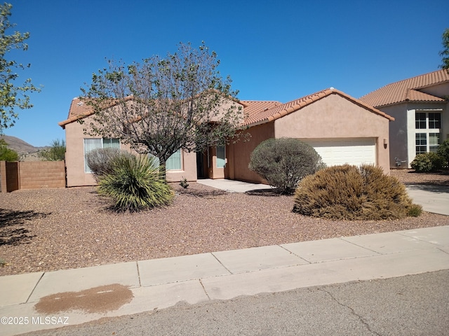 ranch-style house with a garage, a tile roof, and stucco siding