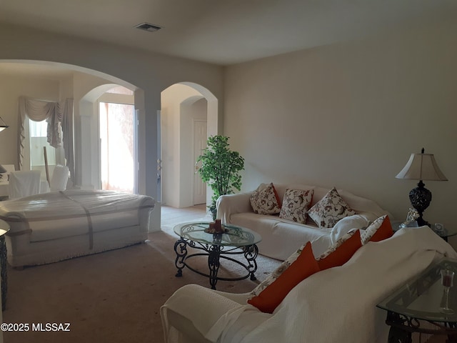 carpeted living area featuring arched walkways and visible vents