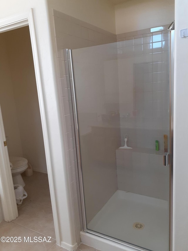 bathroom featuring tile patterned flooring, a stall shower, and toilet