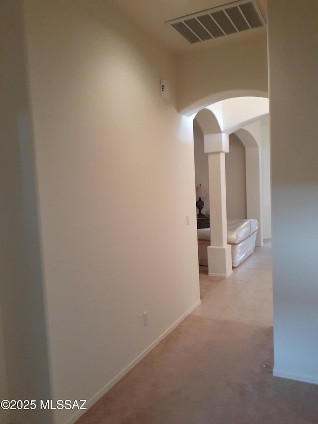 hallway featuring arched walkways, visible vents, carpet flooring, and baseboards